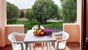 A balcony with a table, chairs, and a fruit bowl with flowers. - Apartment in San Teodoro (San Teodoro)
