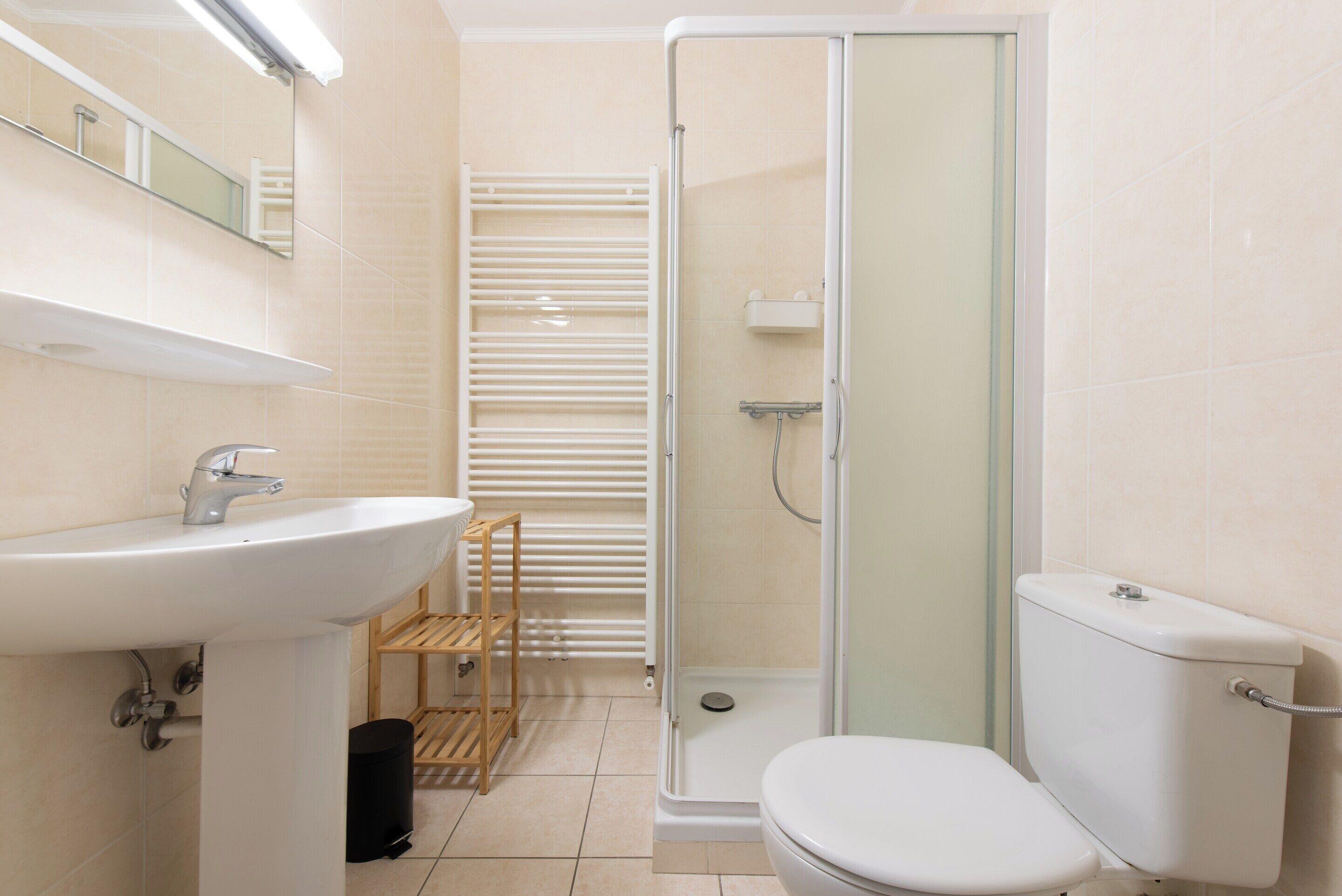Une salle de bain équipée d’un lavabo, de toilettes et d’une douche à parois de verre.
