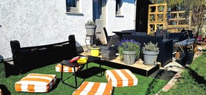 Eine Terrasse mit Gartenmöbeln, einem Tisch und Kübelpflanzen.