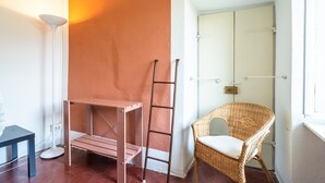 A room with a wooden ladder, a wicker chair, a white floor lamp, and a closed door. - Appartamento in Centro Storico a Cannero Riviera (Cannero Riviera)