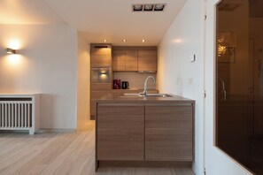 A modern kitchen with wooden cabinets, a built-in oven, and a stainless steel sink. - Apartment in Middelkerke With Sea View (Middelkerke)