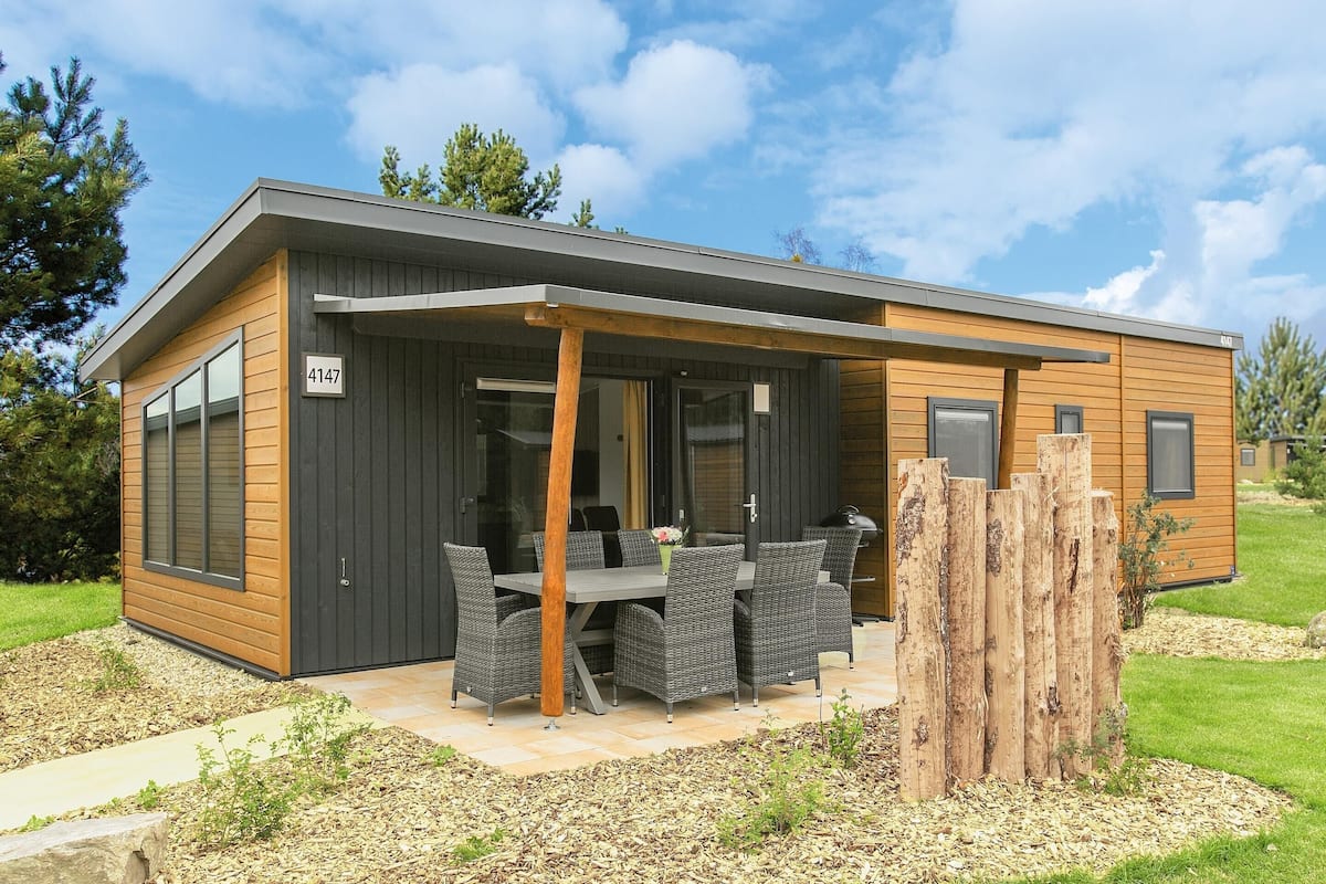 A modern building with a covered patio, a number 4147, and a dining area with wicker furniture.