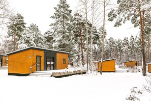 A cabin with a wooden exterior, a door, and a window. - Mobile Home im Tropical Islands Resort (Halbe)
