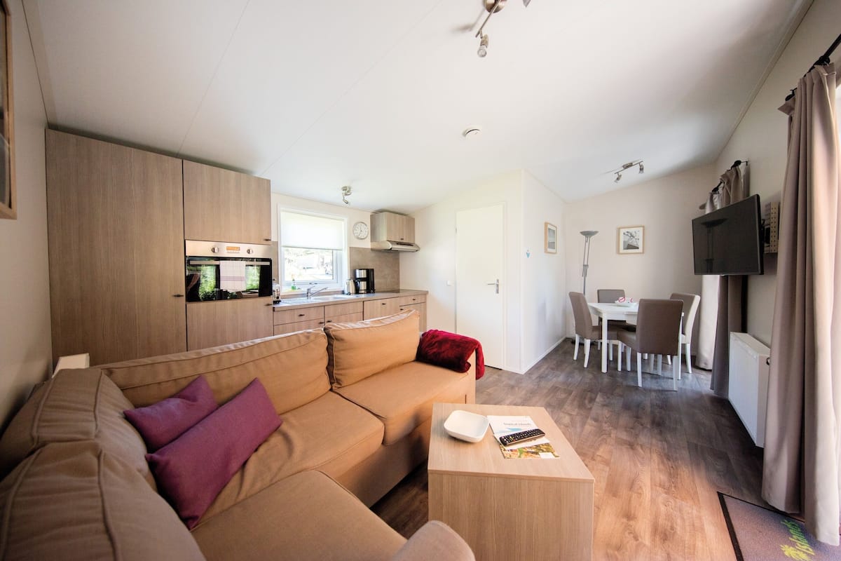 A modern living room with a sofa, a coffee table, and a dining area with a table and chairs.