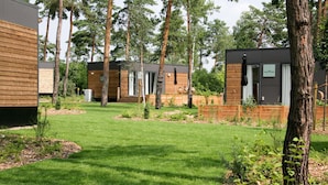 A row of modern cabins with a well-maintained lawn and trees in the background. - Mobile Home im Tropical Islands Resort (Halbe)
