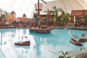 Ein großer Indoor-Wasserpark mit Schwimmbecken, Booten und einer schlossartigen Konstruktion.
