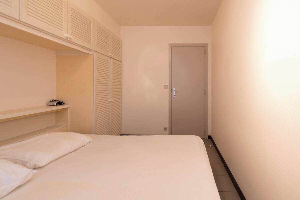 A bedroom with a bed, a wardrobe, and a door.