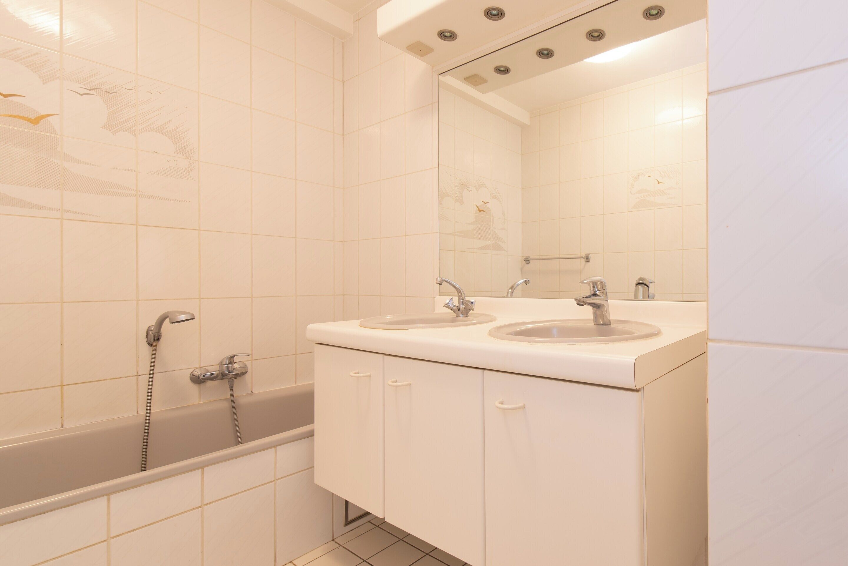 A bathroom with two sinks, a bathtub, and a mirror.