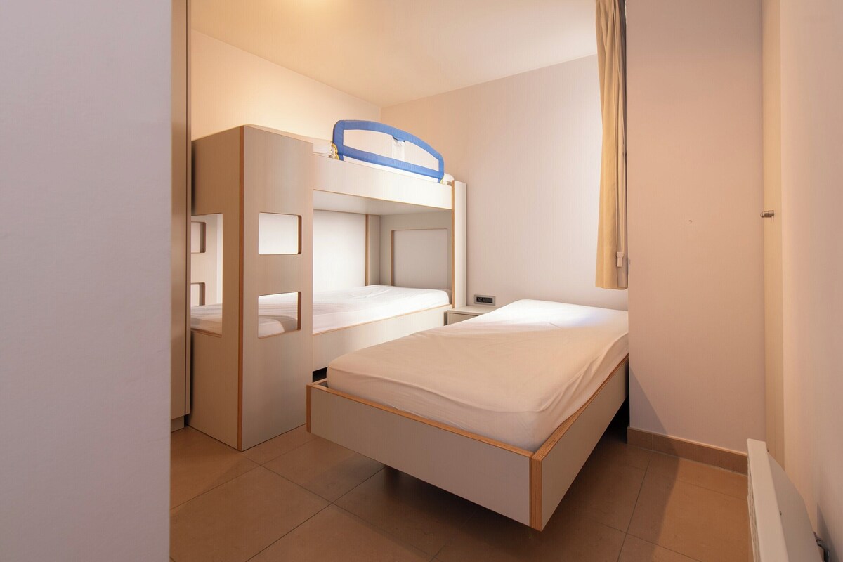 Ein kleines Zimmer mit Etagenbett, Schreibtisch und Stuhl.