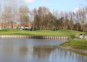 A calm water body with a grassy area and trees in the background. - Apartment in Middelkerke Near Casino (Middelkerke)
