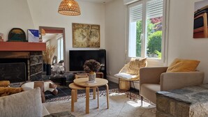 A living room with a fireplace, a television, a stone coffee table, and a sofa with cushions. - Family Home in Locquirec Bay (Locquirec)