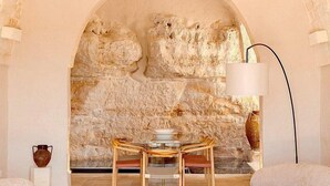 Una habitación acogedora con una pared de piedra, una mesa con sillas y una lámpara.