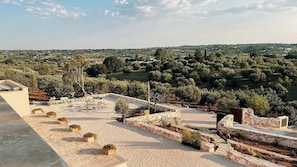 A rooftop terrace with stone walls, potted plants, and a view of a rural landscape. - Villa Petraluce: A spacious three-story villa surrounded by olive groves, with Free WI-FI. (Ostuni)