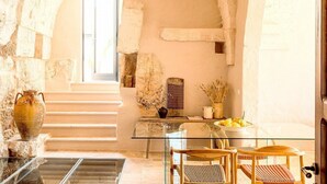 Un interior de paredes de piedra con una mesa de cristal, sillas de madera y un florero.