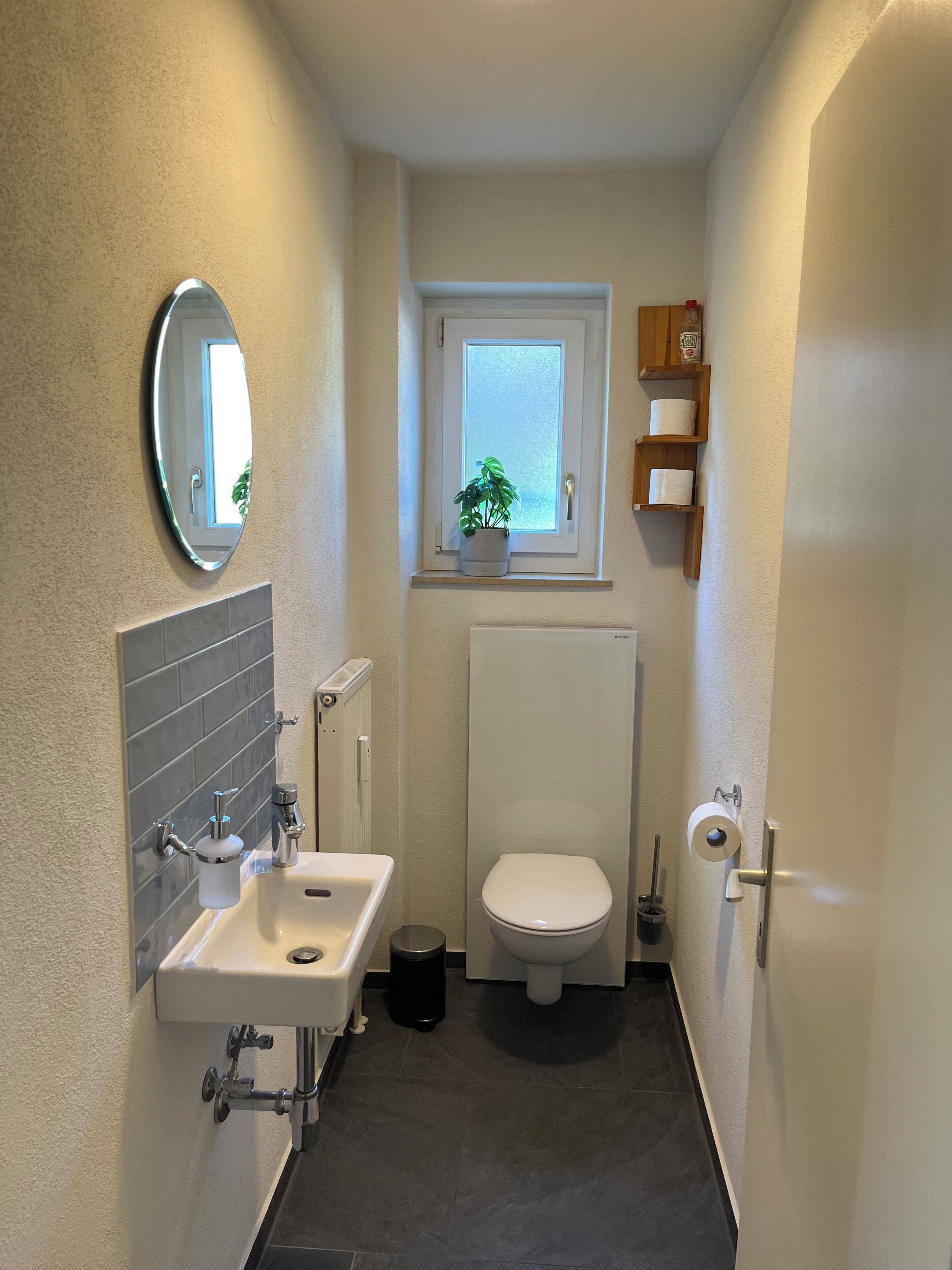 Ein kleines Badezimmer mit einem weißen Waschbecken, einer Toilette und einem kleinen Fenster darüber.