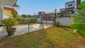 A courtyard with a paved walkway, a potted plant, and a gated entrance. - Alaya Stays 3BHK Riviera Residence Villa (Ambalapuzha)