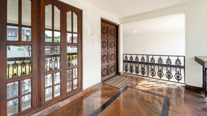 A hallway with a wooden door, a metal railing, and a polished floor. - Alaya Stays 3BHK Riviera Residence Villa (Ambalapuzha)