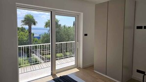 A bedroom with a large sliding glass door leading to a balcony, a bed, and a wardrobe. - Holiday apartment with air conditioning (Crikvenica)