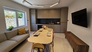 A modern kitchen with a dining area, built-in appliances, and a flat-screen TV. - Holiday apartment with air conditioning (Crikvenica)