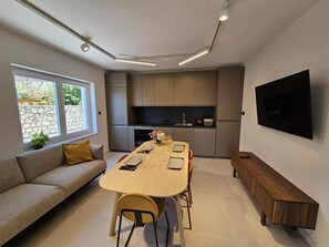 Een moderne keuken met een eethoek, inbouwapparatuur en een flatscreen televisie.