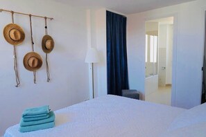 Ein Hotelzimmer mit einem Bett, einer Lampe, einem Stuhl und einer Tür zu einem Badezimmer.