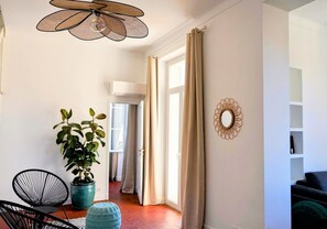 Ein modernes Wohnzimmer mit Deckenventilator, einem Blumentopf, einem runden Spiegel und einem Sofa.