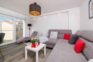 Een moderne woonkamer met een grijze bank, een witte salontafel en een hanglamp.