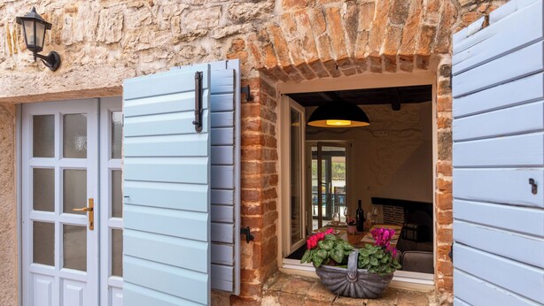 A stone building with a wooden door and shutters, a large window, and a potted plant on the porch. - Finca with pool and garden, pets welcome (Vižinada)
