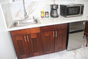 Een keuken met een roestvrijstalen spoelbak, koffiezetapparaat, magnetron en koelkast.