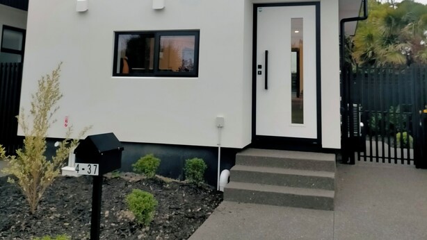 Ett modernt hus i två våningar med en vit fasad, en brun accentvägg och ett svart tak.