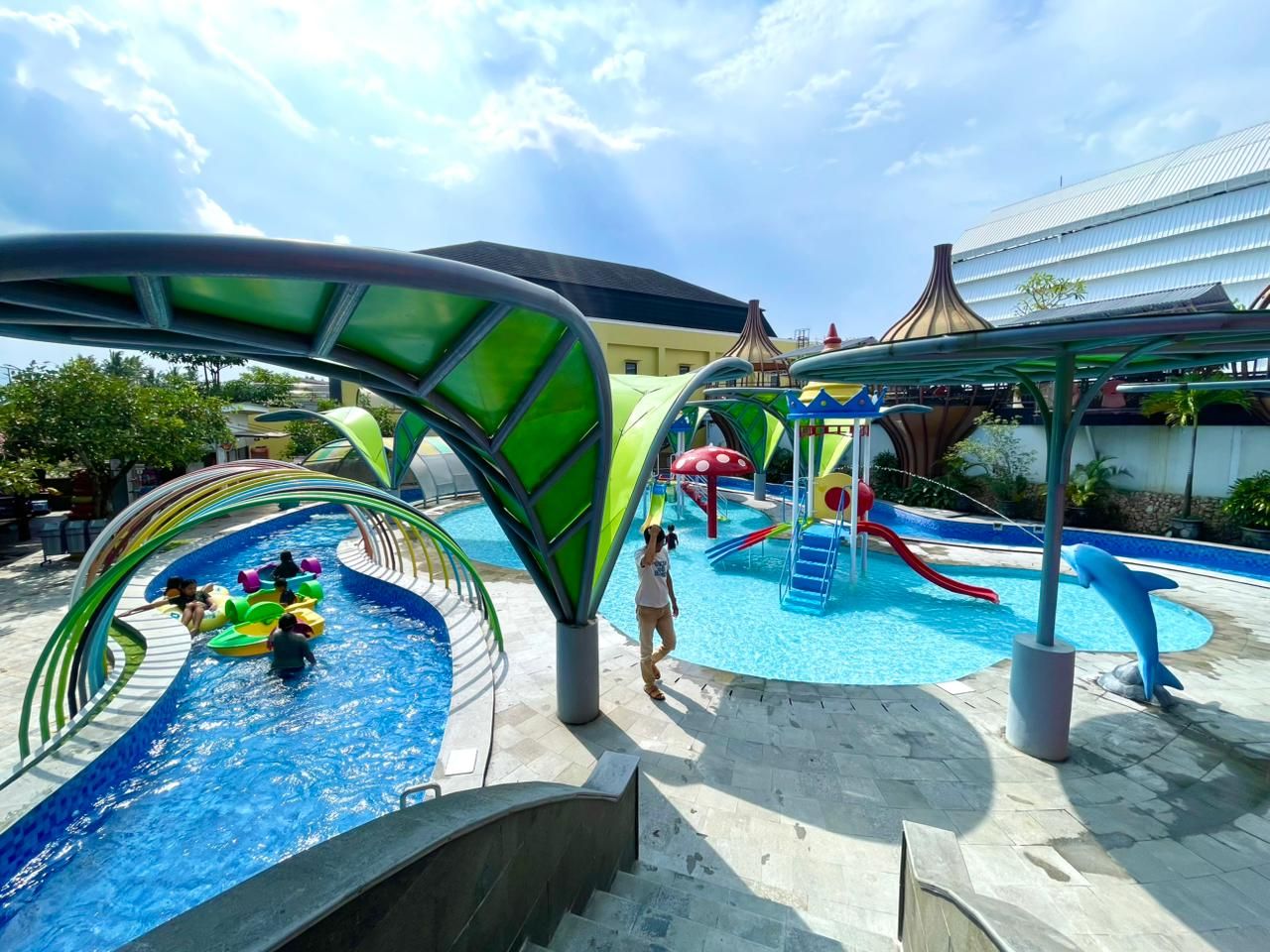 Un parc aquatique avec des toboggans, une piscine et une statue de dauphin.