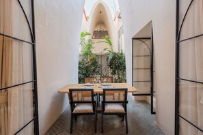 A dining area with a table set for four, surrounded by chairs with woven backs. - ELIVAAS Bogenvilla Luxe 3 BHK Villa (Anjuna)