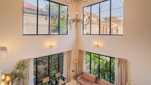 A spacious room with large windows, a chandelier, and a sofa. - ELIVAAS Bogenvilla Luxe 3 BHK Villa (Anjuna)