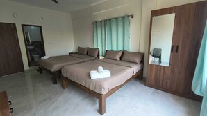 A hotel room with two beds, a wooden wardrobe, a mirror, and a bathroom visible through an open door. - Ameya Coorg (Madikeri)