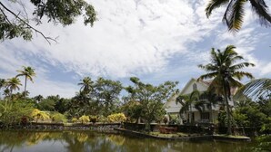 Un paesaggio tranquillo con un lago, una casa, palme e un gazebo.