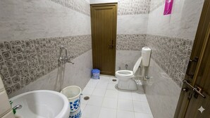 Ein kleines Badezimmer mit Toilette, Waschbecken und einem blauen Mülleimer.