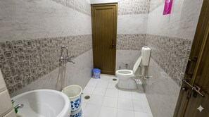 A small bathroom with a toilet, sink, and blue trash bin.