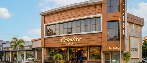 A hotel with a modern design, featuring a prominent entrance, a signboard, and a visible staircase leading to the entrance.