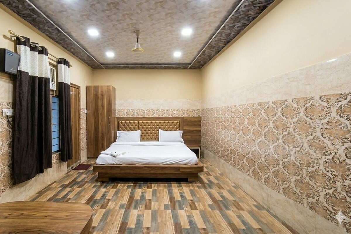Een kamer met een bed, een houten bankje, een wandairconditioner en wandtegels met een patroon.