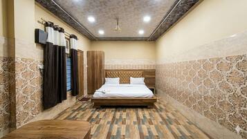 Una habitación con una cama, un banco de madera, un aire acondicionado de pared y baldosas con diseños.