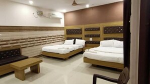 Ein Hotelzimmer mit drei Betten, einer Bank, einem Sessel und einem gefliesten Boden.