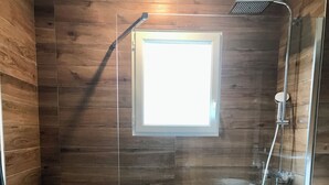 Un baño moderno con ducha, una ventana pequeña y lavamanos.