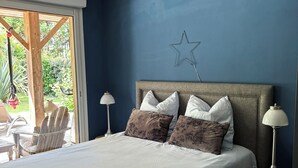 Un dormitorio con cama, almohadas, una decoración de estrella en la pared, una lámpara y vistas al exterior.