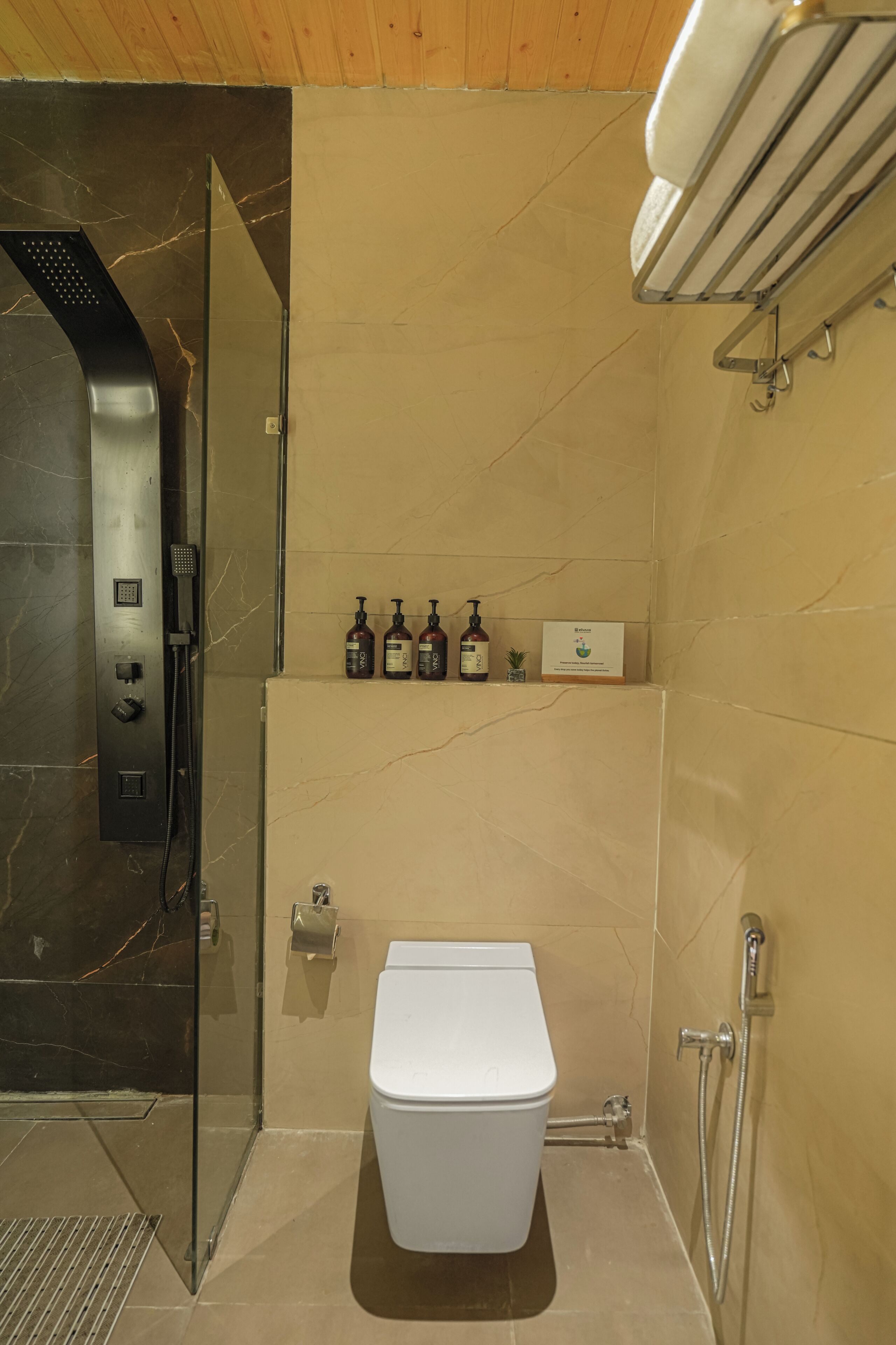 A modern bathroom with a glass shower enclosure, a white toilet, and a shelf with toiletries.