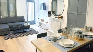A modern apartment with a dining area, kitchen, living room, and a large grey wardrobe.