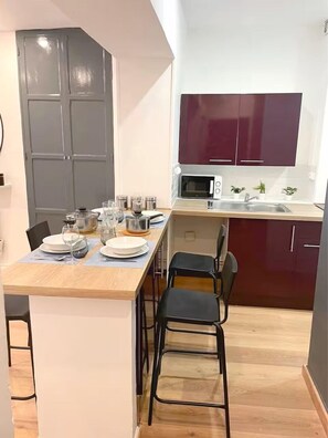 Una cocina compacta con microondas, fregadero y armarios oscuros.
