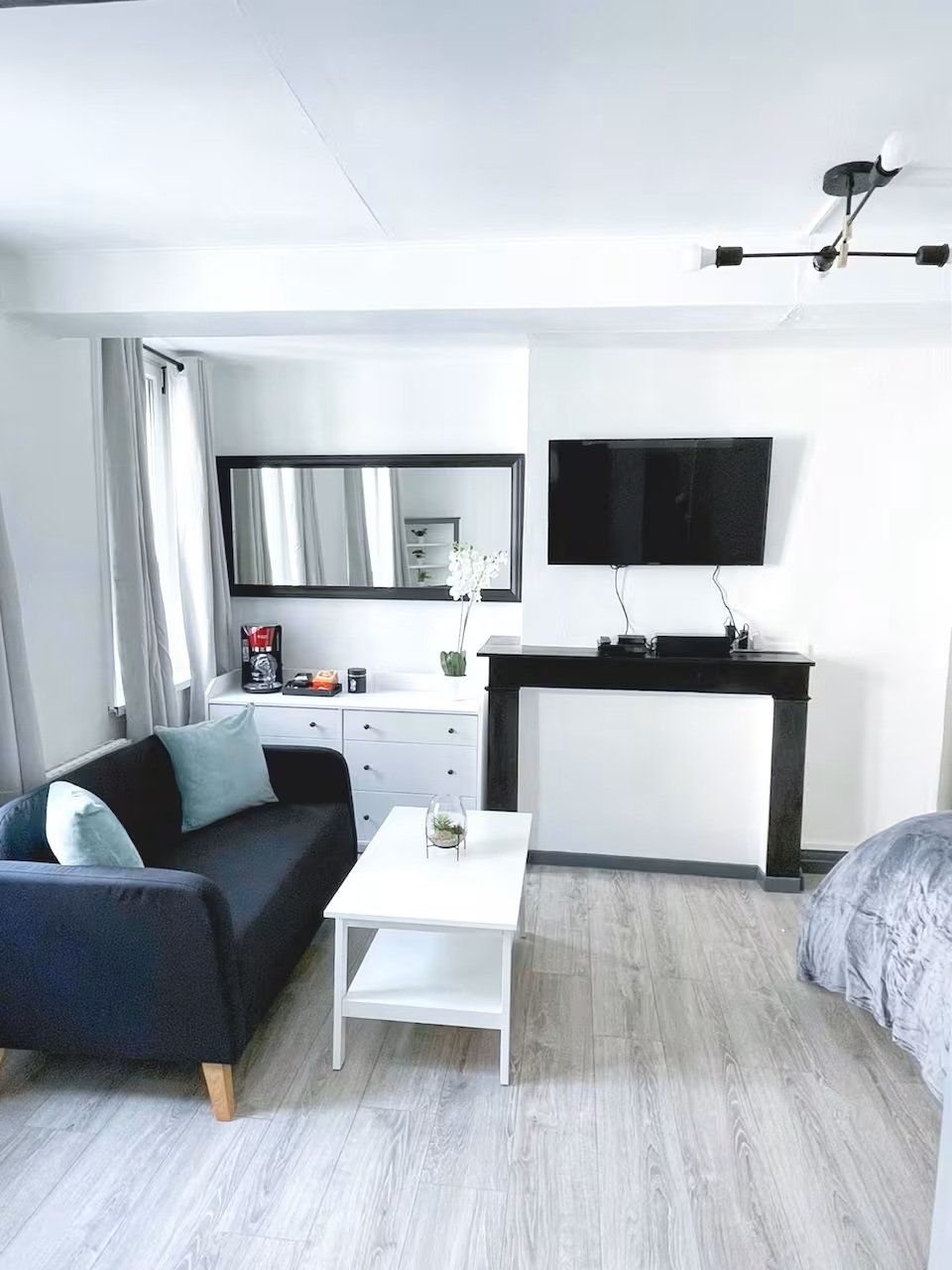 Een moderne hotelkamer met een bank, een klein tafeltje, een televisie, een bureau en een bed.
