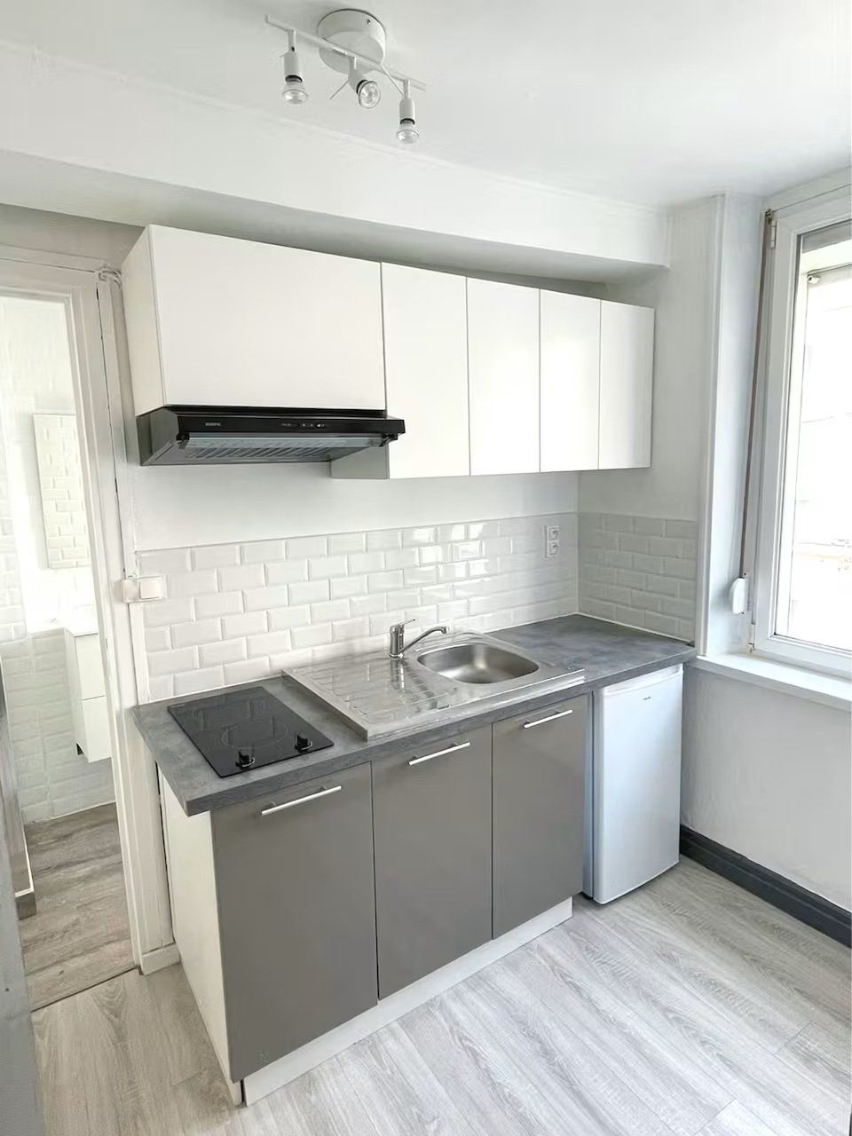 Ett modernt kök med vita skåp, en diskho i rostfritt stål och en inbyggd diskmaskin.