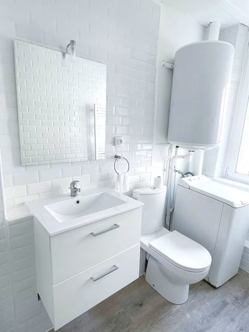 Une salle de bain moderne avec un lavabo blanc, un miroir, des toilettes et un grand réservoir d’eau blanc.