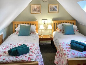Ein Doppelzimmer mit zwei Betten, floralem Bettbezug, passenden Kissen und Nachttischlampen, sowie einer Wanduhr.